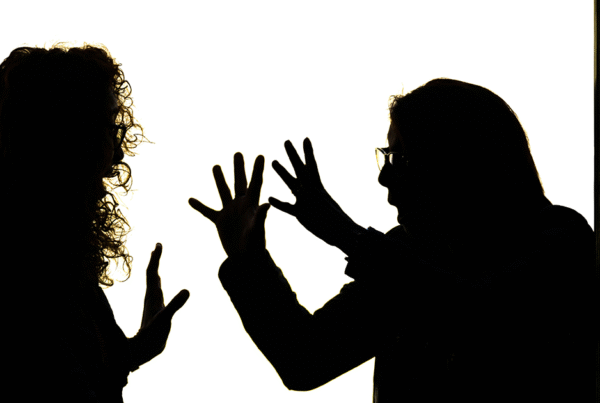 Silhouettes of people, both of whom have their hands up